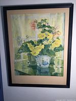 Full framed floral print artwork showing yellow and pink flowers in glass containers on a table with a window background.