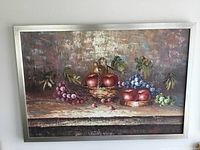 Full view of framed Denny Sweeting oil painting hung on wall showing still life composition of fruit on rustic table.
