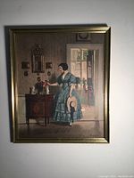 Framed colored lithograph of woman in a blue dress indoors.