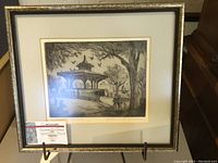 Full view of framed black and white etching by Gordon Kit Thorne depicting Alexander Park, Vancouver Stanley Park, with identifiable pavilion and trees.