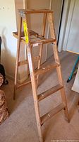 Full view of the 5 ft wooden step ladder showing four steps and metal braces at the top.
