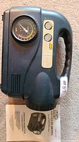 Front view of MVP air compressor showing pressure gauge, control buttons, handle, and part of instruction manual.
