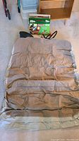 Photo of beige twin size Coleman Quickbed air mattress laid flat on floor, showing horizontal air chambers and slightly wrinkled surface.