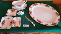 Group photo showing gravy boat on under-plate, three small dishes, oval platter, cheese cutter, and swan toothpick holder arranged on green felt.