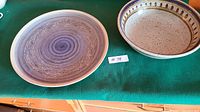 Overview of the two pottery pieces on a green cloth surface, showing the large serving plate and the smaller serving bowl.