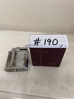 Vintage Ronson lighter and original Ronson box shown side by side from top view.