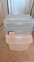 Stack of 3 clear Rubbermaid snap cases and 1 large clear plastic bin underneath, showing size and shape.