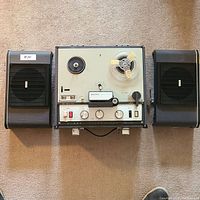 Full view of the Sony TC-200 reel to reel tape recorder with one reel loaded and two external black speakers on either side.