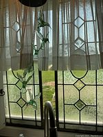 Two decorative glass and lead window panels with geometric diamond pattern visible behind curtain.