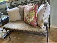 View of the full metal bench with all four cushions in place, showing front and seat area.