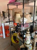Photo showing the full shelving unit with various lamp shades and items on and around it.