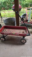 Full side view of the red Radio Flyer wagon showing peeling paint, logo and handle attached.