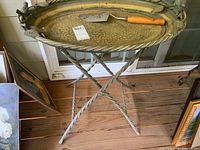 Full view of round metal table with removable tray, resting on twisted metal base with crossed legs.