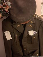 Vintage military uniform jacket and matching peaked cap displayed on hanger