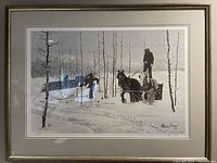 Framed print showing winter scene with horse, sled, two people and snow-covered landscape, signed Allen Sapp.