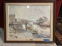 Full front view of framed painting showing coastal scene at low tide with boats, buildings and rocks.
