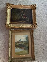 Both framed paintings laid on carpet showing relative sizes and ornate frames