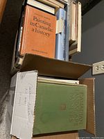 Two boxes filled with various art books focusing on Canadian artists and painting.