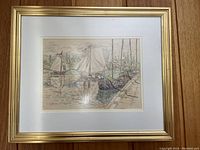 Framed watercolor painting depicting sailboats in a harbor scene within a gold-tone frame and white mat