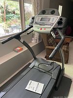 Front view of Sears Freespirit treadmill showing control console, buttons, fans, and manual on the running deck.