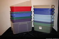 Stack of 15 plastic storage bins in various colors including red, blue, green, purple, tan, and clear, showing overall content of the lot