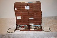 Stack of brown presentation boxes with two open boxes showing collector plates and certificates