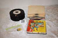 Stack of 45-rpm vinyl records with paper sleeves, and a stack of children's illustrated 45-rpm record covers. Includes two record adapters in plastic bag.