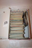 Box filled with hundreds of postcards stacked vertically, showing thickness and quantity.