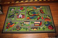 Full view of the children's play mat rug showing roads and buildings arranged in a grid pattern with various colorful illustrations.