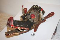 Side view of the vintage African art mask showing the sculpted animal face, painted horns, circular eyes, and open lower jaw.