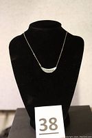 Sterling silver crescent pendant necklace displayed on black jewelry bust.