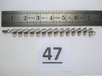 Top view of the sterling silver flower bracelet next to a ruler showing length about 6.5 inches.