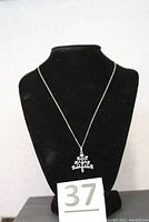 Front view of necklace displayed on black mannequin showing the lovebird tree pendant and chain length.