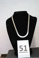 Sterling silver neck chain displayed on black bust stand with lot number card showing 51.