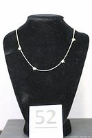 Front view of slender necklace with small star charms displayed on black velvet bust