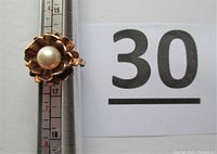 Front view on mandrel showing pearl center and flower petal design next to lot number sign