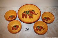 Front view of one large platter and four small bowls decorated with elephants in orange and red tones.