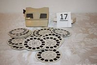 Original Sawyer’s View-Master viewer with 28 vintage circular image discs arranged around it on a table.