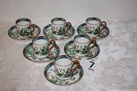 Set of six demitasse coffee cups with matching saucers showing full group arrangement on table.