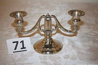 Full view of double arm sterling silver candlestick holder on a fabric surface with lot number card.