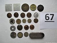 Overview photo showing 26 assorted tokens and coins of various sizes and designs laid out on white background.