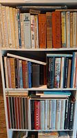 Shelf with various books including cookbooks and historical biographies.