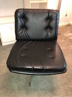 Front view of black leather office swivel chair showing seat and backrest with button tufting.