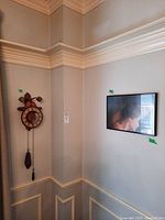 View of corner showing the wood wall clock mounted on the wall and next to it the framed print.