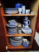 Full cabinet view showing stacked plates, cups, pots and canisters