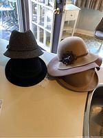 Four hats placed on a white table near a glass door showing the lot contents.
