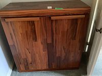 Front view of closed two-door tall boy dresser showing mixed wood veneer pattern