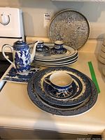 Set of blue and white ceramic platters, cups, and a teapot arranged on a countertop showing overall items and patterns.