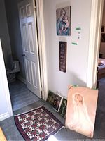 Six art prints stacked or leaning against wall, including religious and classic themes.