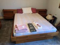 Full view of teak platform bed frame with mattress on carpeted floor